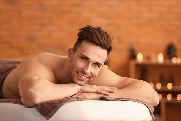 Handsome young man relaxing in spa salon - Photo, image