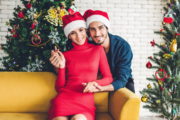 romantisches süßes Paar in Weihnachtsmützen, das Spaß beim Dekorieren des Weihnachtsmannes hat - Foto, Bild