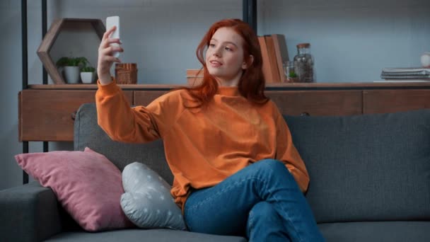 fröhliches Teenager-Mädchen sitzt auf Sofa und macht Selfie - Filmmaterial, Video