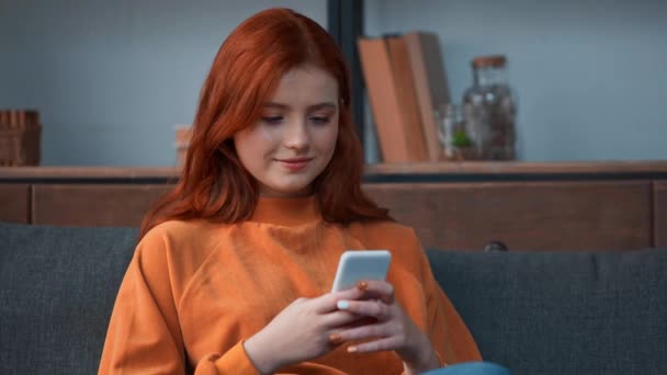 Düşünceli kızıl saçlı genç kız akıllı telefondan konuşuyor. - Video, Çekim