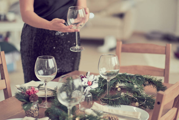 De vrouw wacht op de gasten en dekt de tafel. Feestelijke ligtafel, voorbereiding voor kerstdiner. - Foto, afbeelding