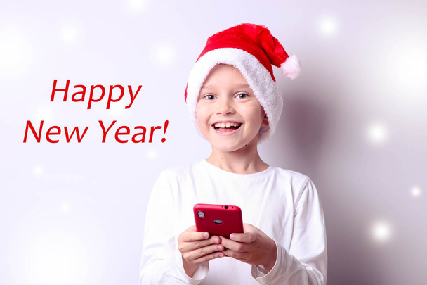 Niño en un sombrero de Santa con un teléfono inteligente
 - Foto, imagen