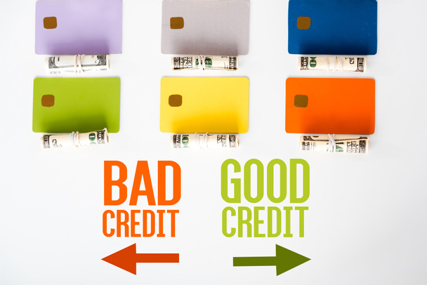 верхний вид шаблонов кредитных карт рядом с наличными рулонами с банкнотами доллара и буквами на белом
  - Фото, изображение
