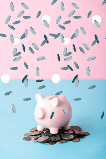 falling silver coins near piggy bank on blue and pink  - Photo, Image