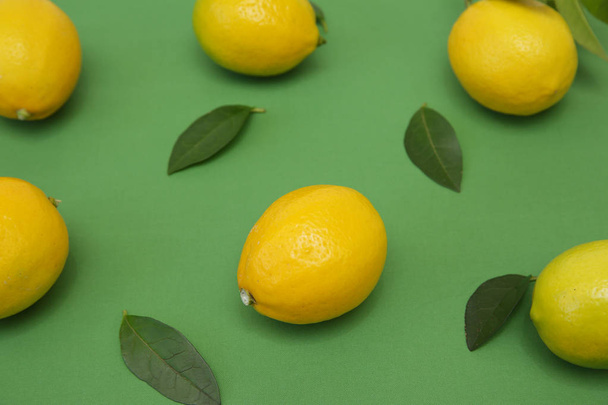 juicy lemons with leaves on a green background. Organic citrus fruits for a healthy diet. Tropical fruit. Pattern, background. - Φωτογραφία, εικόνα