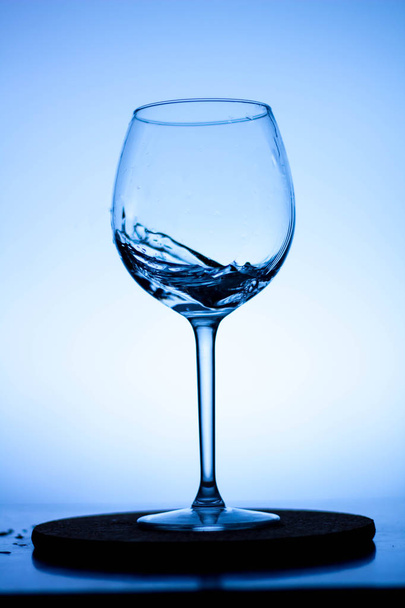 a splash of liquid in a glass wine glass. water pouring inside a glass wine glass. a curl of water in a wine glass. drink in a glass wine glass .splash in the glass - Фото, изображение