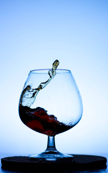 a splash of liquid in a glass wine glass. water pouring inside a glass wine glass. a curl of water in a wine glass. drink in a glass wine glass .splash in the glass - Zdjęcie, obraz