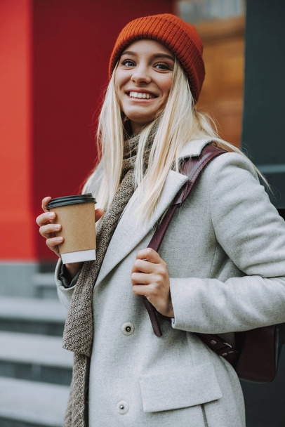 Young lady with coffee to go and smiling - Foto, afbeelding