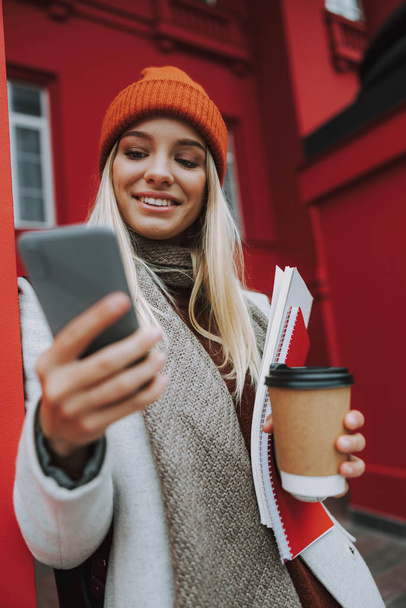 Young female student using modern smartphone and smiling nice - Foto, Bild
