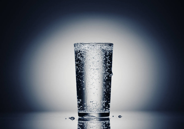 lasillinen kuohuvaa vettä tummansinisellä pohjalla
 - Valokuva, kuva