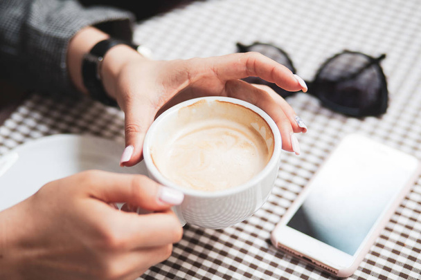 Frauenhände halten eine Tasse Kaffee mit Schaum über Holztisch, Draufsicht - Foto, Bild