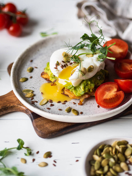 Zdrowe pożywne śniadanie naleśnika ziemniaczanego, tłuczone awokado, gotowane jajka, kiełki grochu i różne nasiona na ceramicznym talerzu - Zdjęcie, obraz