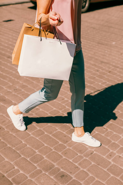 Foto recortada de una mujer con bolsas de papel caminando sola
 - Foto, Imagen