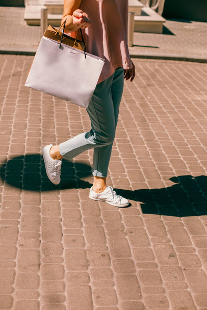 Cropped photo of a woman walking in the street with colorful paper bags - Фото, зображення