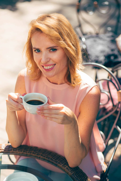 Joyful woman smiling and looking relaxed with a cup of coffee - Фото, зображення