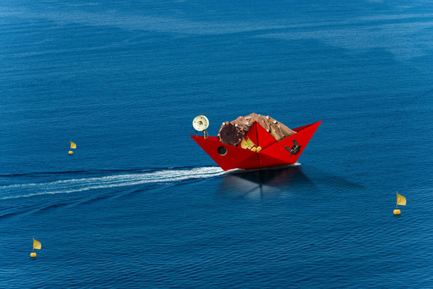 Bateau de pêche en papier rouge avec filets de pêche navigue dans la mer bleue
 - Photo, image