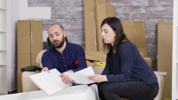 Couple reads instructions for assembly of furniture in new house - Footage, Video