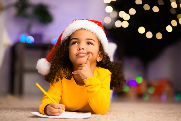 Niña afro Wistful poco pensando en carta a Santa Claus
 - Foto, imagen