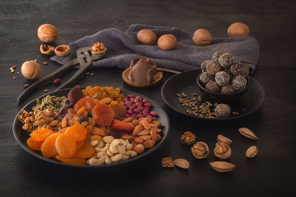 Sekoita kuivattuja hedelmiä, energianpuremia, suklaatahnaa ja pähkinöitä mustalla pöydällä. Matala avain
 - Valokuva, kuva