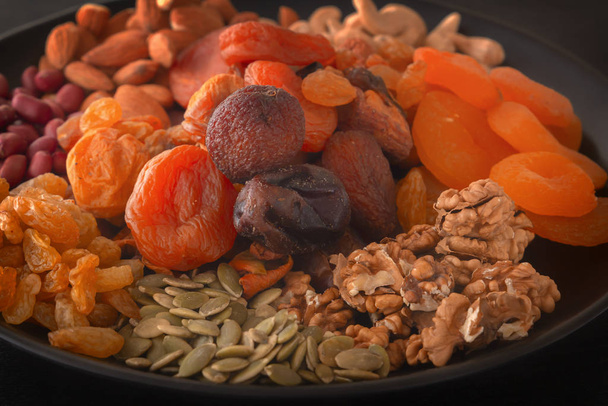 Mix of dried fruits and nuts on a black table. Close-up - Photo, Image