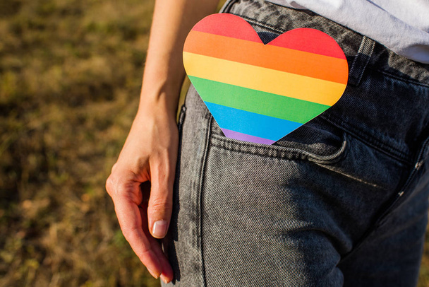 Woman holds in hands a heart in the colors of the rainbow. Young beautiful girl. LGBT history month. Pride Month. Lesbian Gay Bisexual Transgender. LGBT flag. Love, human rights, tolerance. LGBTQ+ - Fotografie, Obrázek