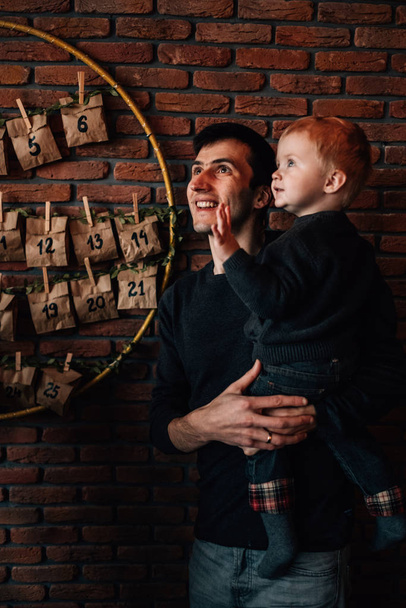 Retrato de un niño pequeño con su papá en la habitación decorada en el tema de Navidad
 - Foto, imagen