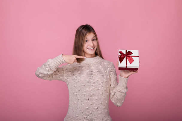 Cute girl points a finger at a box with a gift. - Фото, изображение