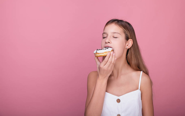 The girl closed her eyes and eats a donut with pleasure. - Fotó, kép
