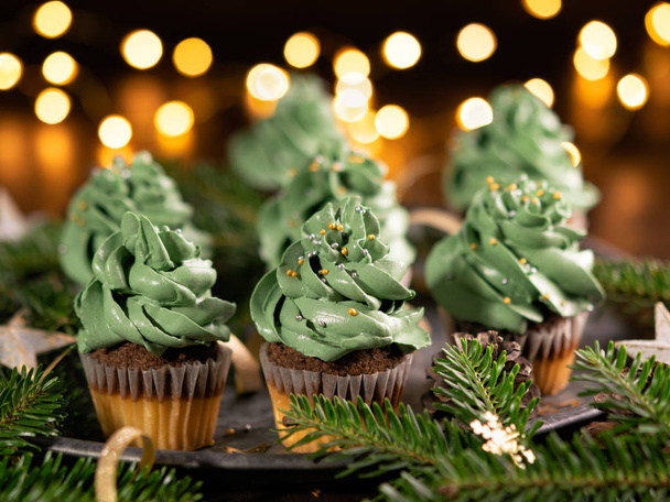 grüne Weihnachtskuchen mit Streusel auf hölzernem Hintergrund mit Lichtergirlanden Bokeh, Kopierraum. Nahaufnahme. Weihnachten und Neujahr Feiertage Hintergrundkonzept. - Foto, Bild