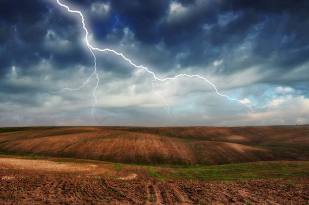 Bouřka v poli. obrovský blesk nad kopcovitým polem. špatné počasí v terénu - Fotografie, Obrázek