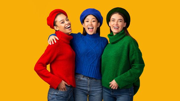 drei glückliche multiethnische Mädchen umarmen sich im Studio stehend, Panorama - Foto, Bild