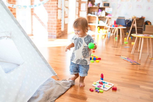 Adorable niño jugando alrededor de un montón de juguetes en el jardín de infantes
 - Foto, imagen