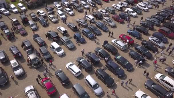 Вид с воздуха на многие припаркованные автомобили и людей, гуляющих по рынку автомобилей или парковки. - Кадры, видео