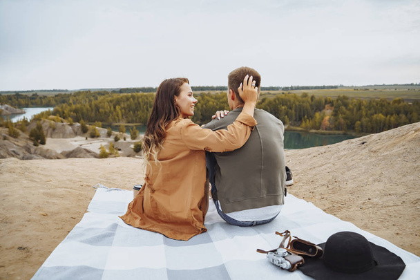 Happy couple sitting on a plaid and enjoying nature view. - Photo, Image