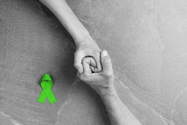 Руки тримають зелену стрічку, рак лімфоми. - Фото, зображення