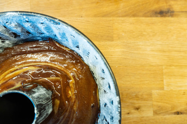 木製のテーブルで焼く前に液体チョコレートケーキの完全なケーキの形 – トップビュー - 写真・画像
