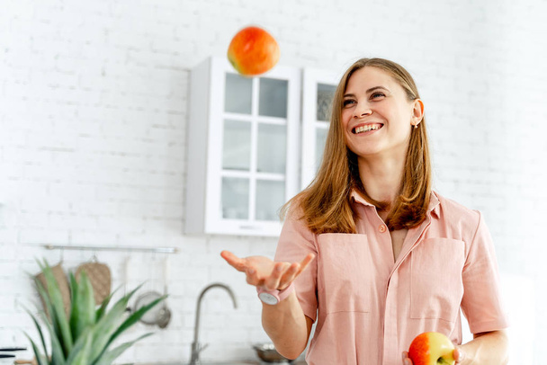 幸せな若い女性ジョギングオレンジでキッチン背景、選択的フォーカス、クローズアップ - 写真・画像