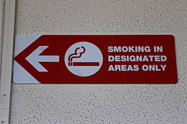 letrero grande que muestra el área de fumar, fondo de pared de color blanco
 - Foto, Imagen