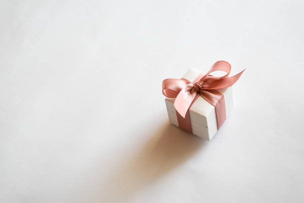 weiße Geschenkschachtel mit rosa Schleife auf weißem Hintergrund. Weihnachten oder Valentinstag weiß Geschenkbox mit rosa Schleife. - Foto, Bild