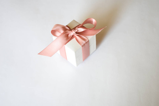 Белая коробка с розовой лентой на белом фоне. Рождество или День Святого Валентина Белая подарочная коробка с розовой лентой
. - Фото, изображение