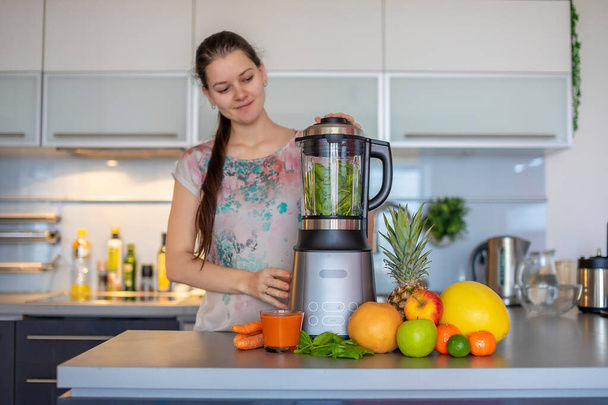 Mujer haciendo batidos verdes con licuadora en la cocina casera, concepto de estilo de vida saludable
 - Foto, Imagen