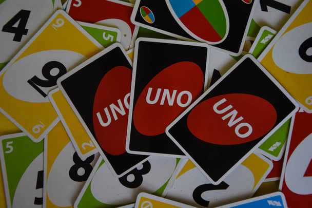 İngiltere, Londra - 4 Aralık 2019 Uno oyun kartları masanın her tarafına saçıldı. Amerikan kart oyunu. Simgesel olarak düzenlenmiş unno iskambil kartları - ters. - Fotoğraf, Görsel