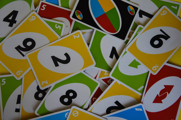 İngiltere, Londra - 4 Aralık 2019 Uno oyun kartları masanın her tarafına saçıldı. Amerikan kart oyunu. Simgesel olarak düzenlenmiş unno iskambil kartları - ters. - Fotoğraf, Görsel