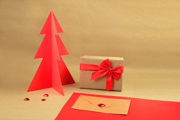 Подарочная коробка и конверт с красной древесной елкой на коричневом фоне
 - Фото, изображение