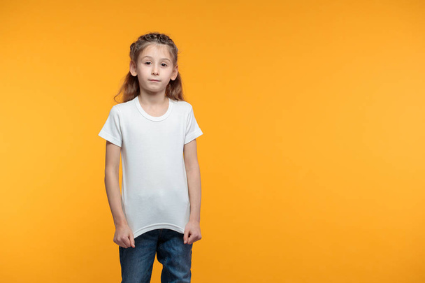 Kid girl wearing white t-shirt with space for your logo or design over yellow texture - 写真・画像
