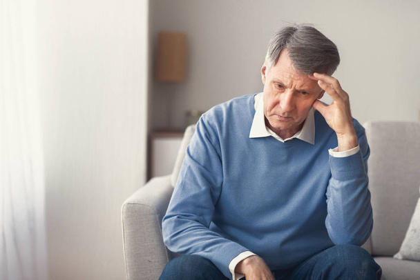 Nešťastný starší muž přemýšlí o odchodu do důchodu sedí na pohovce - Fotografie, Obrázek