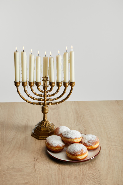 herkullisia donitseja lähellä polttava kynttilöitä menorah hanukka eristetty valkoinen
 - Valokuva, kuva