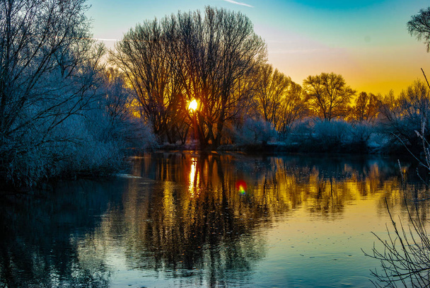 Ένα ποτάμι νωρίς το πρωί του χειμώνα κατά τη διάρκεια πολύχρωμης ανατολής - Φωτογραφία, εικόνα