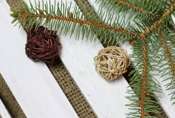 Fir branch and decorative balls on a background of wooden boards. The boards are painted white. - Photo, Image