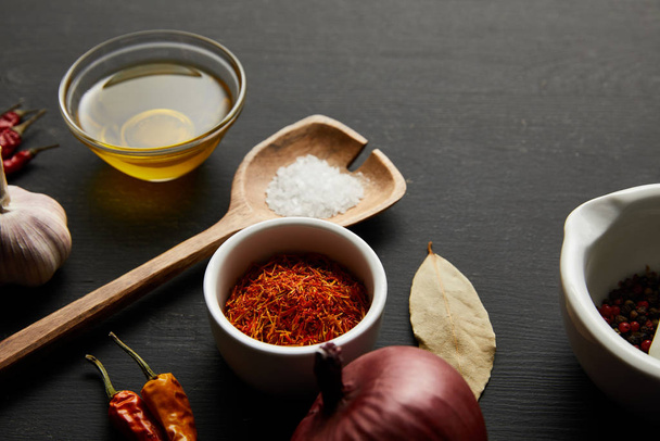 Chili-paprikat suolalla, oliiviöljyllä ja sipulilla mustalla puupohjalla
 - Valokuva, kuva